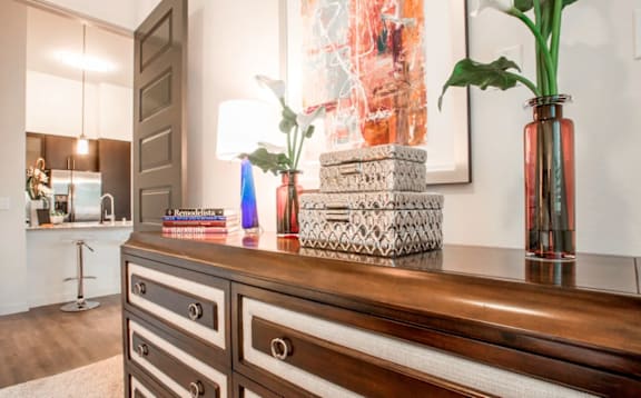 A brown dresser with a stack of books and a plant on top.