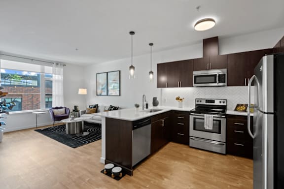 A modern kitchen with dark brown cabinets and stainless steel appliances at The Parker Apartments in Portland, OR