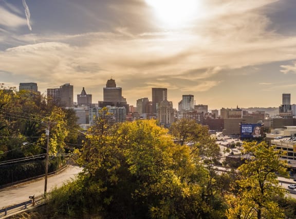 a cityscape with trees in the foreground and a sunset in the background at Adams Edge Apartments, Cincinnati