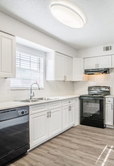 a kitchen with white cabinets and black appliances