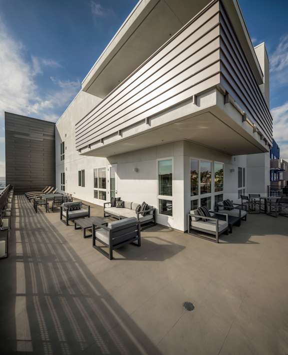 A modern building with a white and black striped facade and a patio with several chairs and tables.