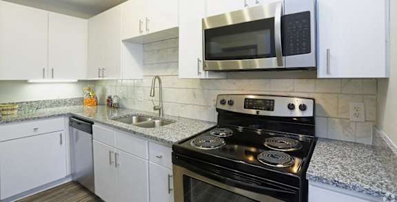 A kitchen with a black stove top oven and white cabinets.