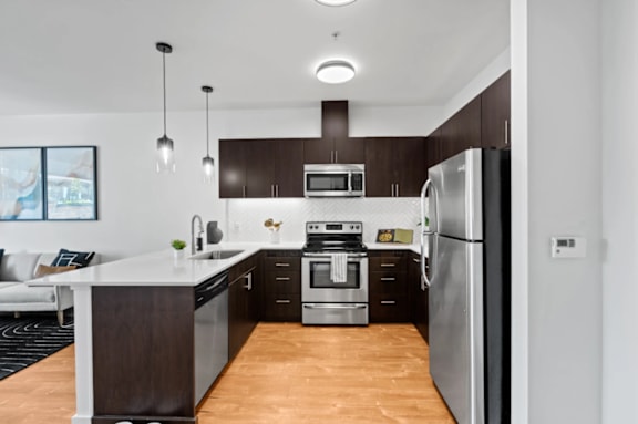A modern kitchen with dark brown cabinets and stainless steel appliances at The Parker Apartments in Portland, 97209