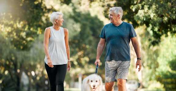 an older couple walking their dog in the park