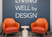 Thumbnail 16 of 18 - two orange chairs in front of a wall with living well by design at Shoreline Grove Apartments in Branford CT.