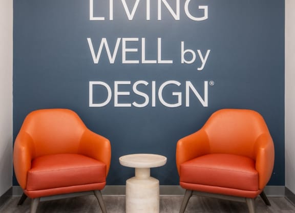two orange chairs in front of a wall with living well by design at Shoreline Grove Apartments in Branford CT.