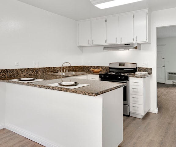 A kitchen with white cabinets and a granite countertop.