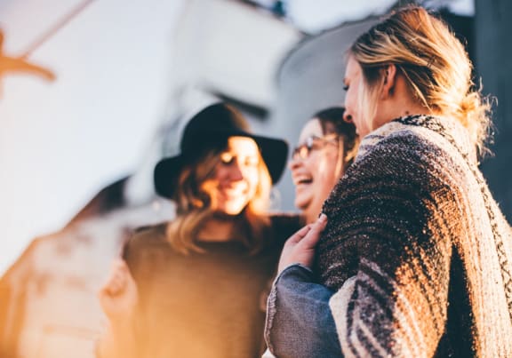 a group of women standing next to each other and laughing