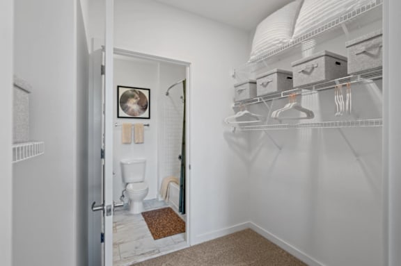 A white bathroom with a toilet and a walk in closet at The Parker Apartments in OR 97209