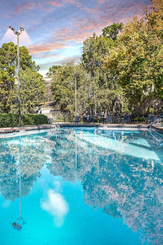 a swimming pool with trees in the background and a cloudy sky