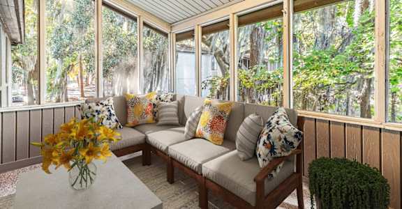 a screened porch with a couch and a table with flowers