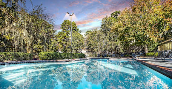 a swimming pool with trees in the background and a cloudy sky