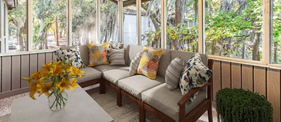 a screened porch with a couch and a table with flowers