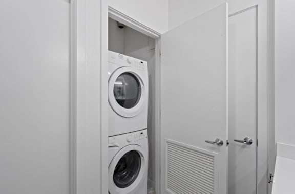 A white laundry room with a washer and dryer at The Parker Apartments in Portland, Oregon