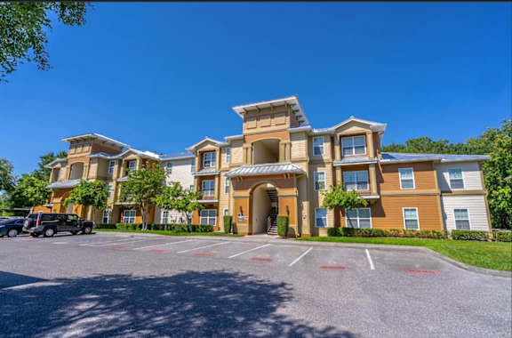 A large apartment complex with a parking lot in front.