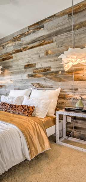 A bedroom with a white bed and a wooden wall.