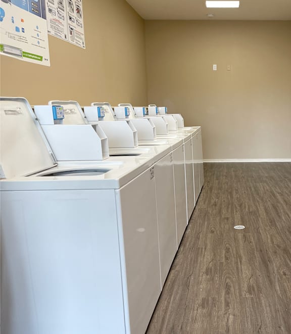 a communal laundry room with washers and dryers and a row of white machines