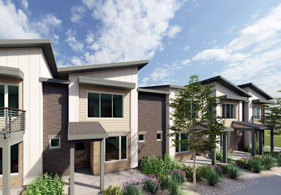 A row of modern houses with balconies and greenery in front.