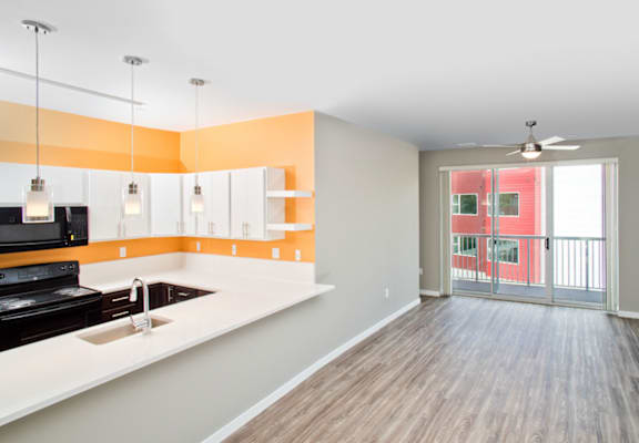 a kitchen and living room with a glass door to a balcony