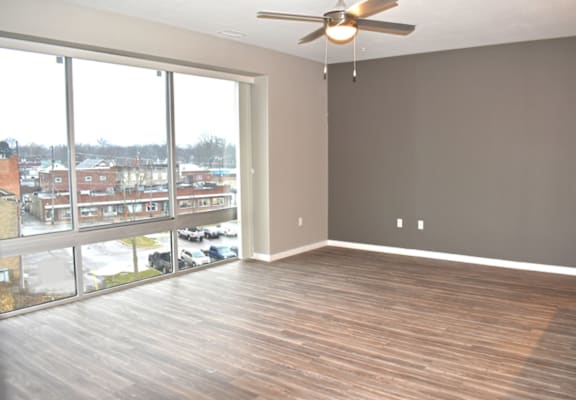 an empty living room with a large window and a ceiling fan