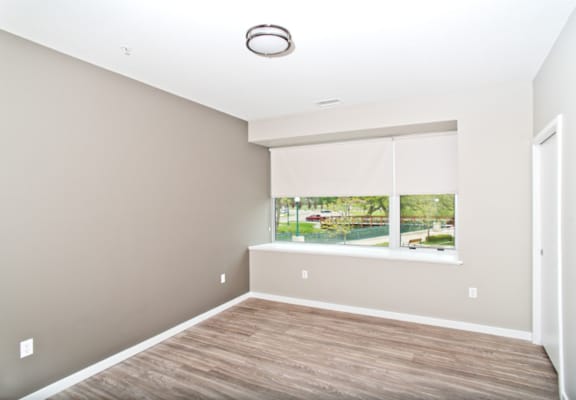 an empty room with a window and a wooden floor