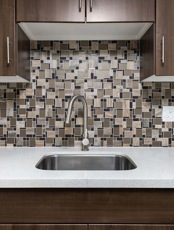 A kitchen with a sink and a tiled backsplash.