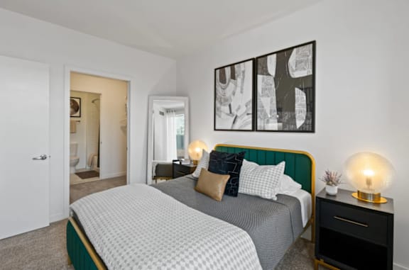 A bedroom with a bed, nightstand, and a painting on the wall at The Parker Apartments in Portland, OR