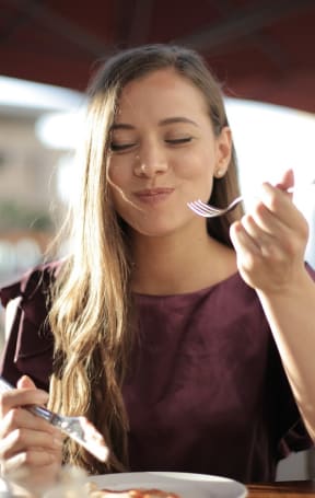 a woman eating a bowl of food with a fork and knife