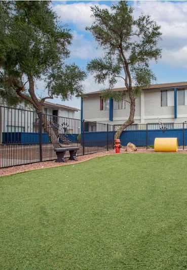 A grassy area in front of apartment buildings with a red fire hydrant.