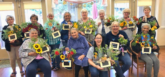 A group of women are holding up flower arrangements at Castle Vista Senior Duplex Community Apartments, Atwater