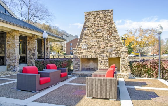 a patio with couches and a fireplace in front of a house