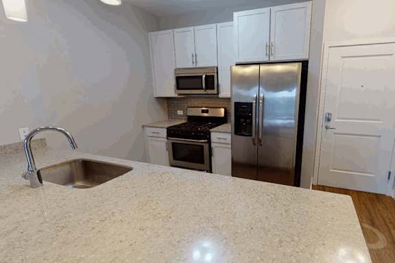 A kitchen with a sink, stove, oven, and refrigerator.