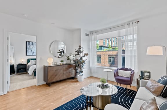 A modern living room with a large mirror, a wooden dresser, and a round coffee table at The Parker Apartments in Portland, Oregon
