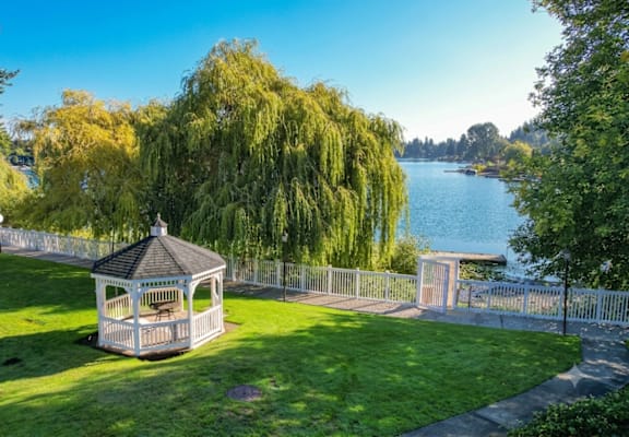 A gazebo sits in a grassy area next to a lake.