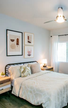 A bedroom with a bed, nightstand, and a mirror.
