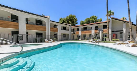 A swimming pool in front of a building with a palm tree at Tides on East Cactus Apartments, Phoenix, 85032