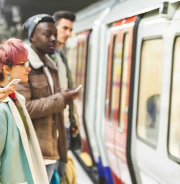 A woman with pink hair waits on a subway platform.