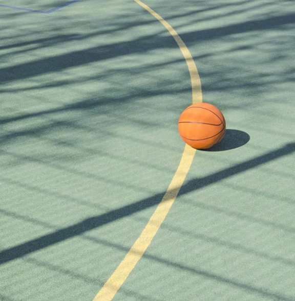 A basketball is on a court with a yellow line.