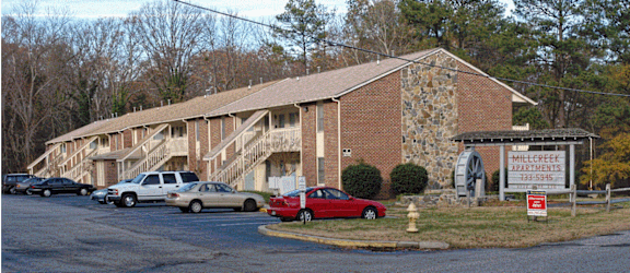 a large brick building with a stone chimney and a parking lot in front of it