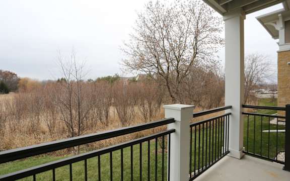 A balcony with a black railing and a white column.