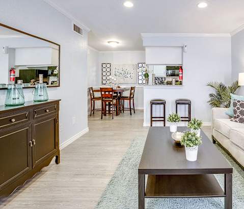 A living room with a couch, coffee table, and a dining table.