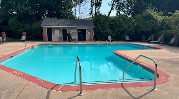 A small pool with a red border and a small building in the background.