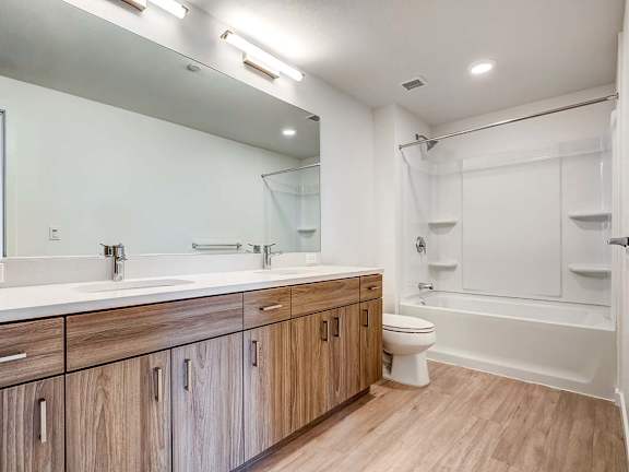 A modern bathroom with wooden cabinets and a white bathtub.