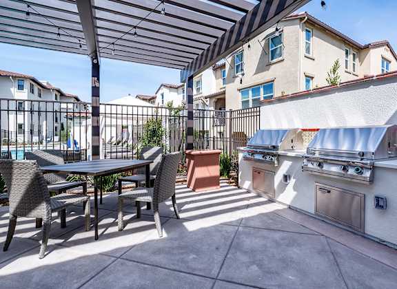 A patio with a table and chairs and a grill.