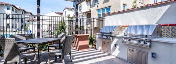 A patio with a table and chairs and a grill.