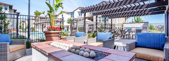 A patio with a table, chairs, and a potted plant.