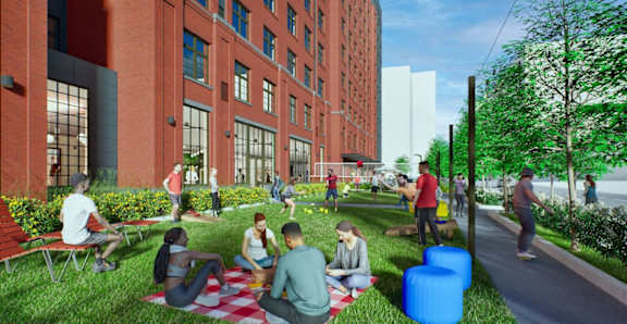 A group of people are sitting on a blanket in a park. at University Commons in Pittsburgh, PA
