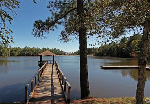 A wooden pier extends into a calm lake surrounded by trees.