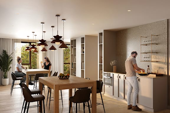 A man is cooking in a modern kitchen with a dining table and chairs.