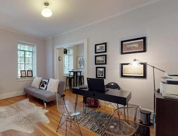 a living room with a couch and a desk with a laptop